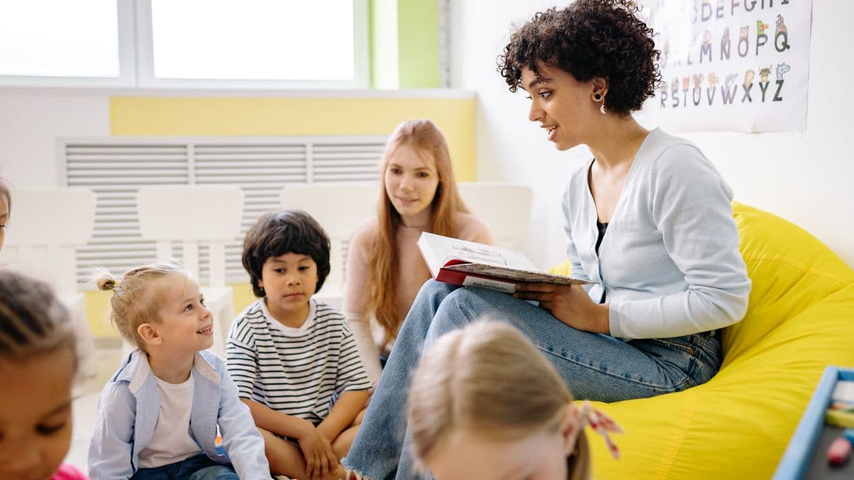 Educator reading an illustrated story to a small group of children during circle time